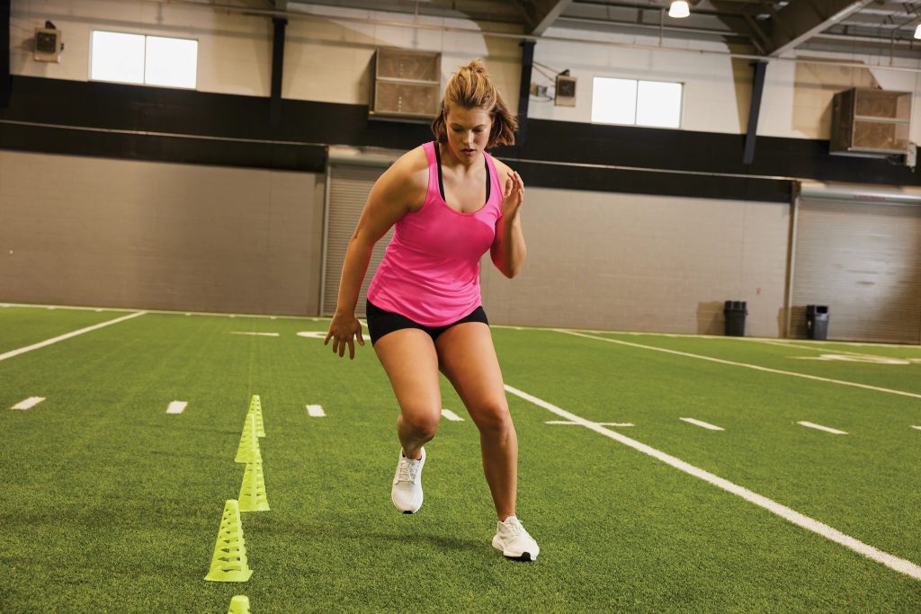 Female track and field athlete wearing Sport-Tek LST356 PosiCharge Competitor Tank, designed for lightweight speed and moisture control.