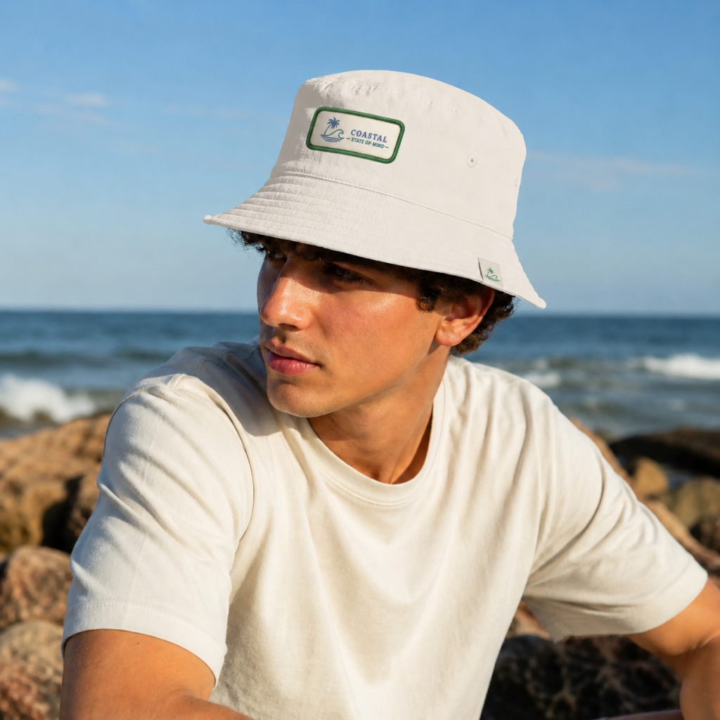 AS Colour Nylon Bucket Hat 1171 featuring a custom embroidered patch on the front and a folded woven label on the brim in an Apliiq-generated mockup.